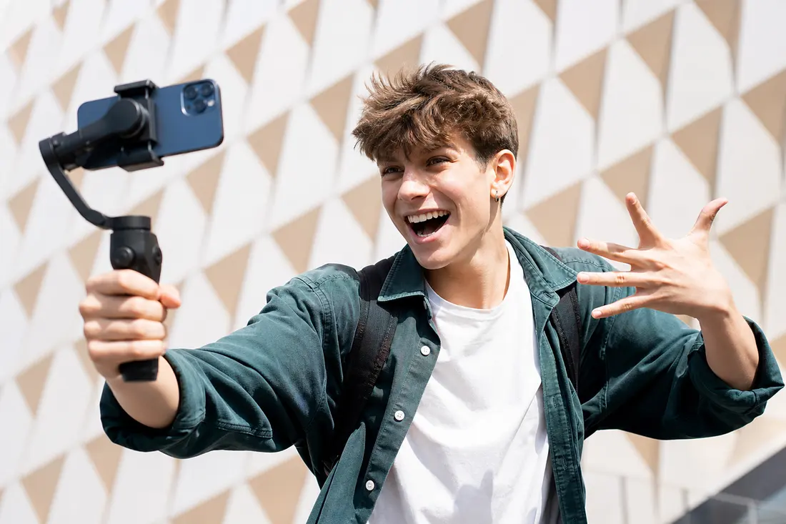 Jeune personne filmant une vidéo avec son smartphone en extérieur, ambiance réseaux sociaux dynamique