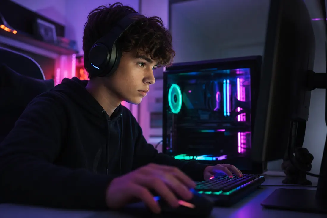 Joueur concentré devant un PC gamer avec setup coloré et écran de jeu allumé