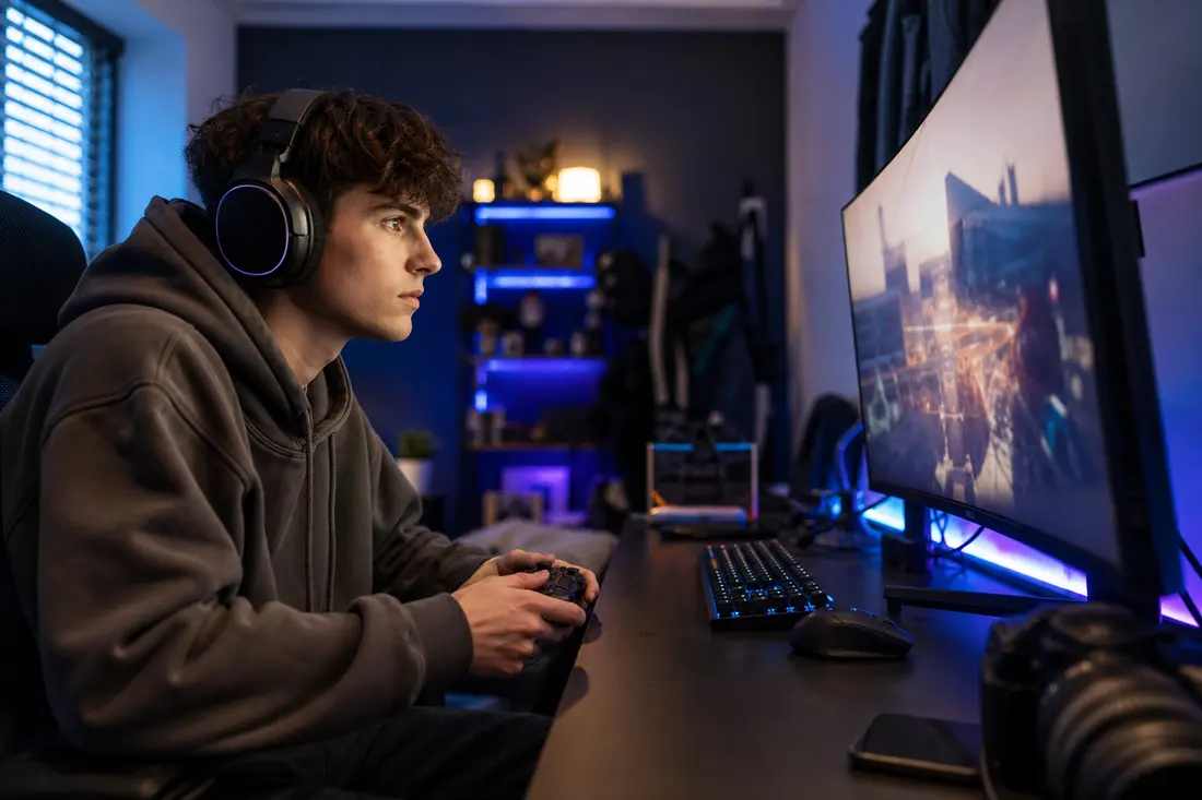Jeune gamer devant son écran, manette en main, avec un jeu vidéo encore en développement affiché