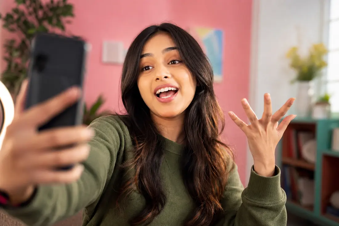 Jeune créateur de contenu filmant une vidéo avec son téléphone en mode selfie, ambiance réseaux sociaux colorée