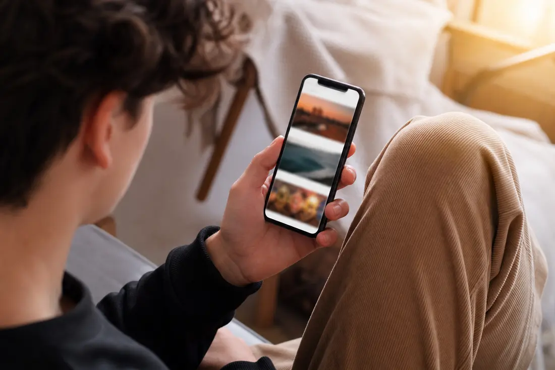 Une main tient un smartphone affichant un profil de réseau social avec une zone de commentaires vide