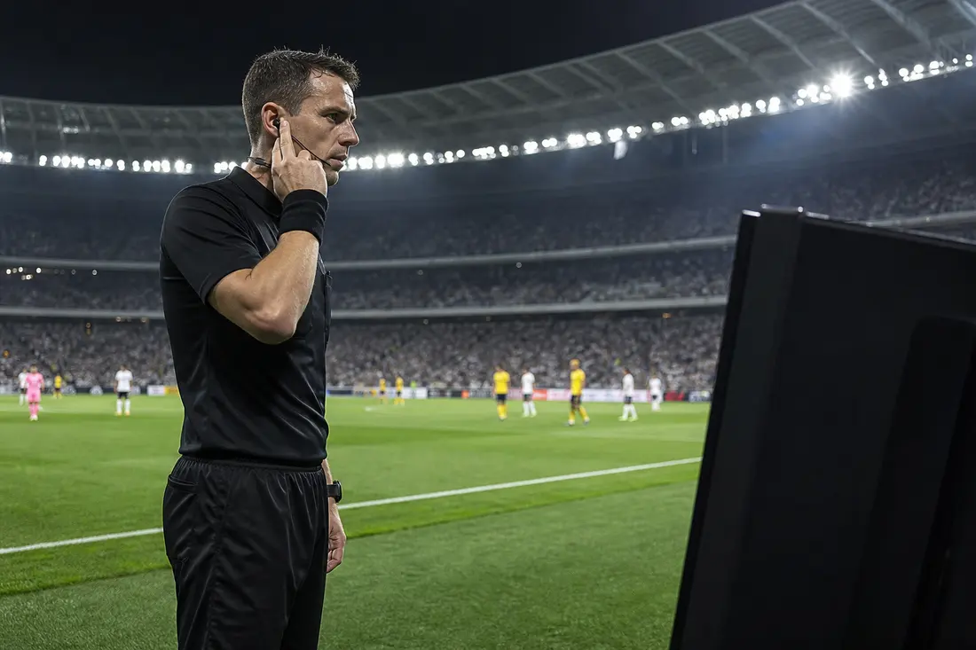 Arbitre de football consultant un écran vidéo au bord du terrain sous les projecteurs du stade